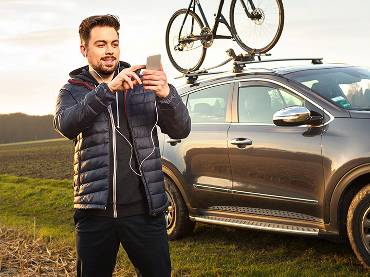 Man holding is a smartphone and searching for the best route to have a drive with his mountain bike 